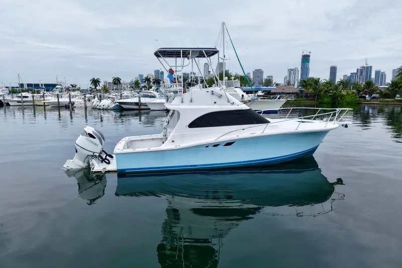Slide: The Image of 1994 Luhrs 32 Convertible boat docked in a marina with city skyline background. - 30