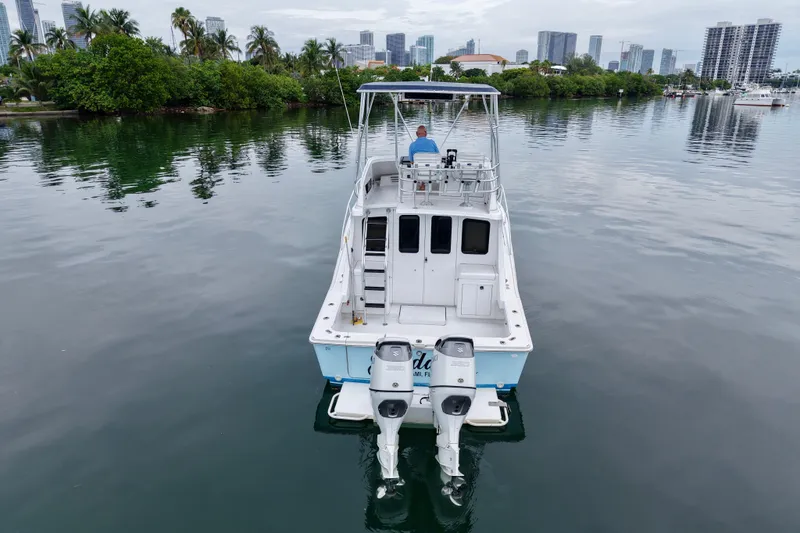 Slide: The Image of 1994 Luhrs 32 Convertible boat on calm water with city skyline in background. - 32