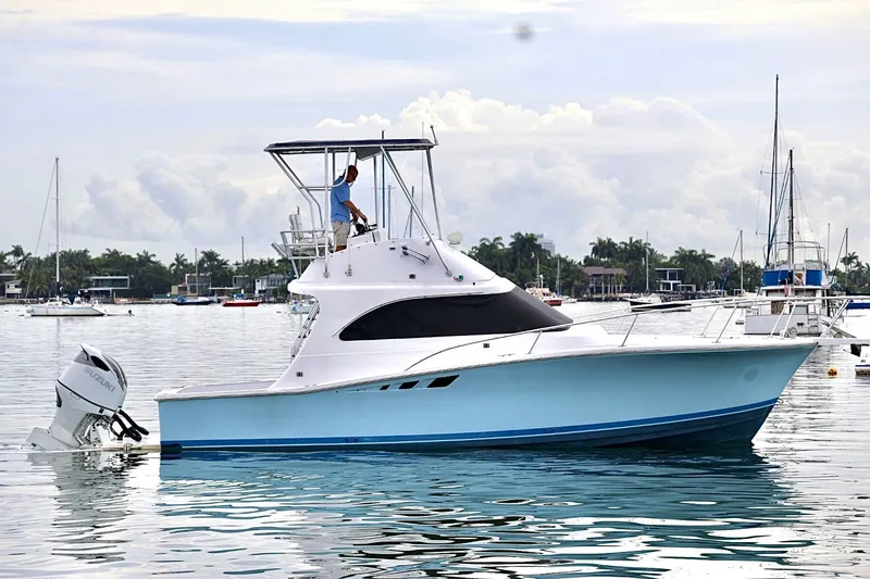 Slide: The Image of 1994 Luhrs 32 Convertible boat on calm water with a person on deck. - 54