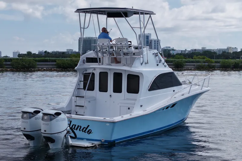 Slide: The Image of 1994 Luhrs 32 Convertible boat with dual Suzuki engines on calm water. - 53