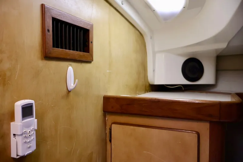 Slide: The Image of 1994 Luhrs 32 Convertible interior with wooden vent, control panel, and storage cabinet. - 65