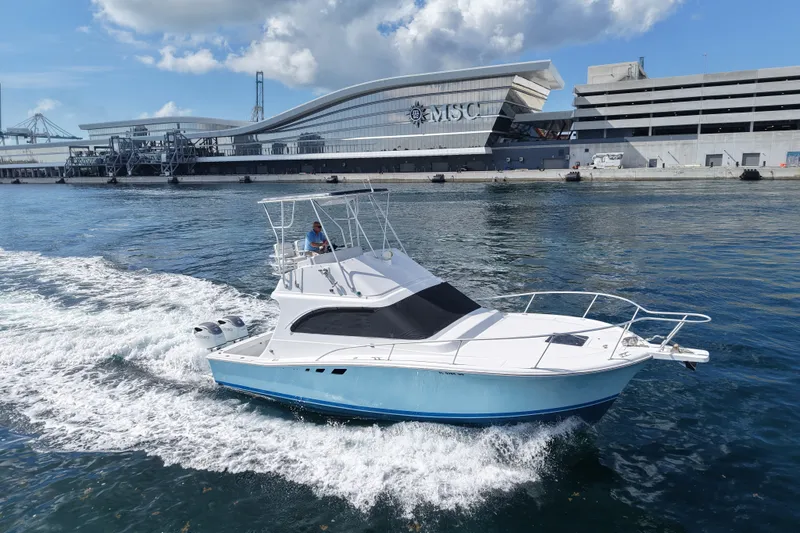 The Image of 1994 Luhrs 32 Convertible boat cruising near a modern port terminal. - 51