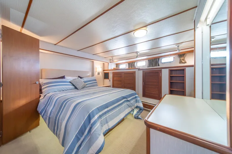 Slide: The Image of Luxurious bedroom interior of 1991 Tollycraft 57 Pilothouse Motor Yacht with striped bedding. - 24