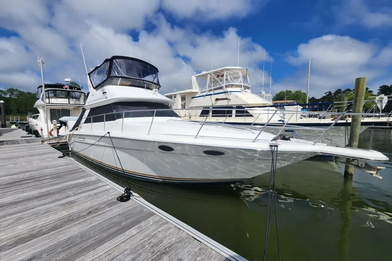 The Image of 1996 Sea Ray 370 Sedan Bridge yacht docked at a marina under a blue sky. - 1