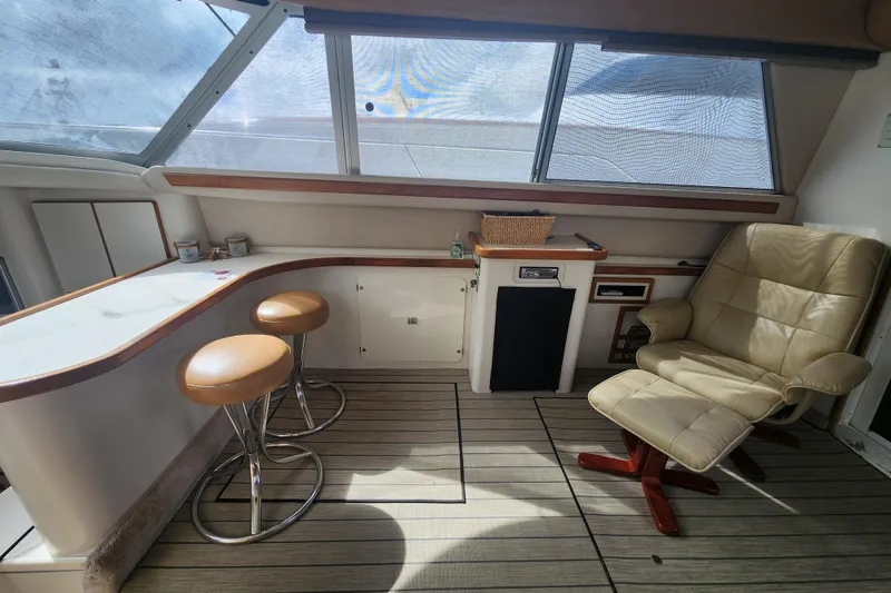 Slide: The Image of Interior of 1996 Sea Ray 370 Sedan Bridge with bar stools and a recliner chair. - 18