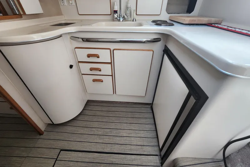 Slide: The Image of 1996 Sea Ray 370 Sedan Bridge kitchen with white cabinetry and compact appliances. - 26