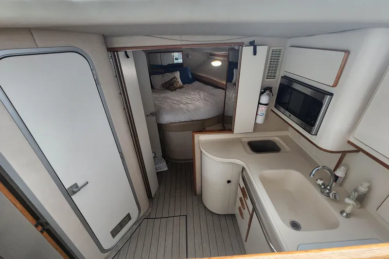 Slide: The Image of Interior of 1996 Sea Ray 370 Sedan Bridge, featuring kitchen and cozy sleeping area. - 45