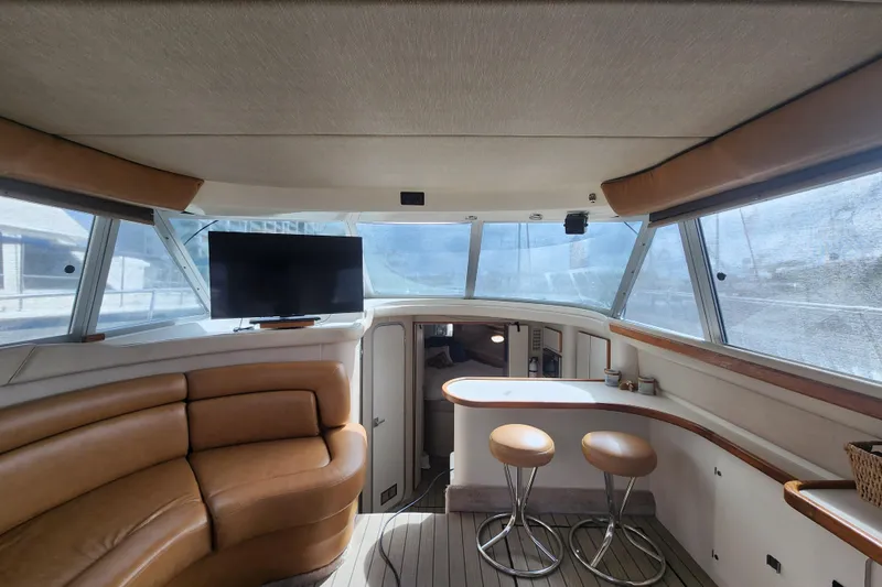 Slide: The Image of Interior of 1996 Sea Ray 370 Sedan Bridge with seating, bar stools, and TV. - 46