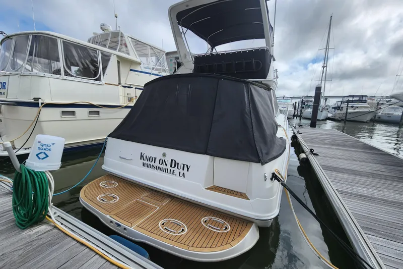 Slide: The Image of 1996 Sea Ray 370 Sedan Bridge docked, featuring a covered stern and wooden deck. - 56