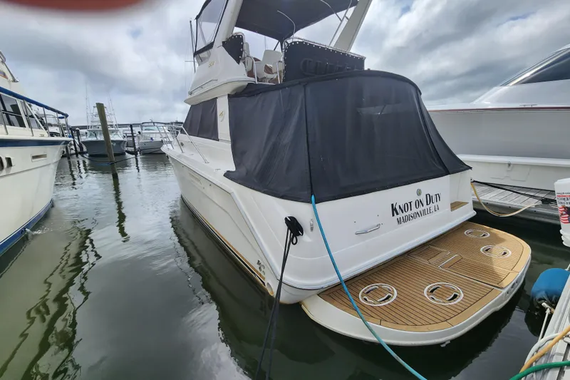 Slide: The Image of 1996 Sea Ray 370 Sedan Bridge docked, featuring a covered deck and "Knot on Duty" name. - 60