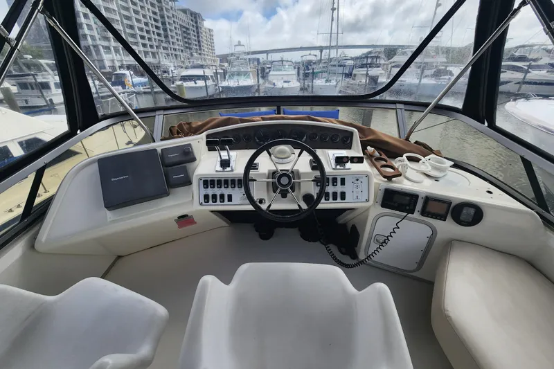 Slide: The Image of 1996 Sea Ray 370 Sedan Bridge helm with marina view, featuring navigation controls and seating. - 7