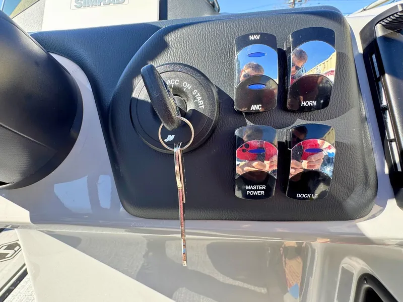 Slide: The Image of Close-up of a 2027 Harris Cruiser 230 helm with ignition key and control switches. - 20