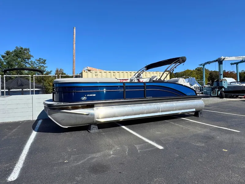 Slide: The Image of A blue Harris Cruiser 230 pontoon boat is parked on a lot under a clear sky. - 1