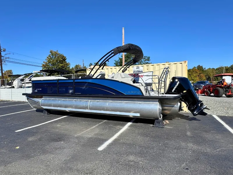 Slide: The Image of Harris Cruiser 230 from 2027 in a parking lot. It has a blue hull and a black motor. - 3