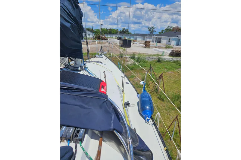 Slide: The Image of 1986 C & C 29 SL sailboat deck with blue fender, docked near construction site. - 17