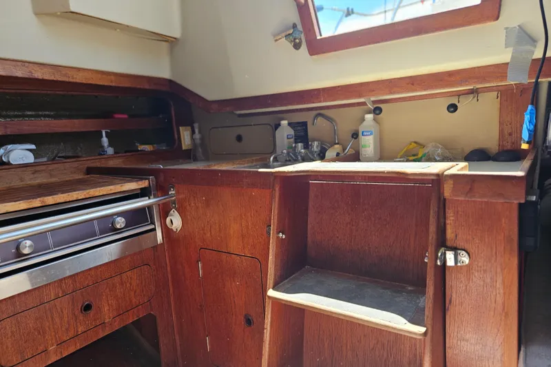 Slide: The Image of 1986 C & C 29 SL sailboat interior kitchen with wooden cabinetry and stainless steel appliances. - 25