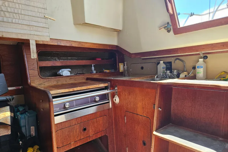 Slide: The Image of Interior of 1986 C & C 29 SL sailboat showing wooden cabinetry and compact kitchen area. - 26