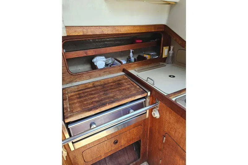 Slide: The Image of 1986 C & C 29 SL sailboat galley with wooden cabinetry and compact appliances. - 27