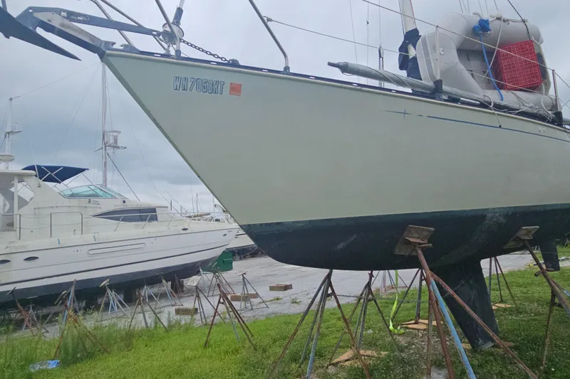 Slide: The Image of 1986 CNC 29 SL sailboat on stands in a boatyard, with overcast sky. - 3