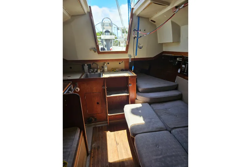 Slide: The Image of Interior of a 1986 C & C 29 SL sailboat, featuring cozy seating and a compact kitchen area. - 33