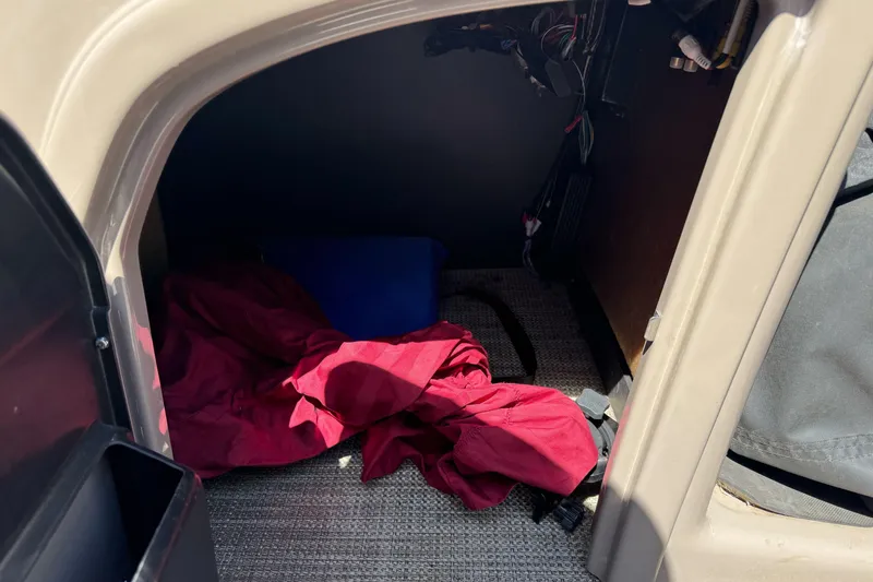 Slide: The Image of Storage compartment in a 2020 Ranger 200F boat with red fabric and blue container. - 21