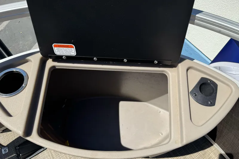 Slide: The Image of Open storage compartment on a 2020 Ranger 200F boat, featuring cup holder and warning label. - 24