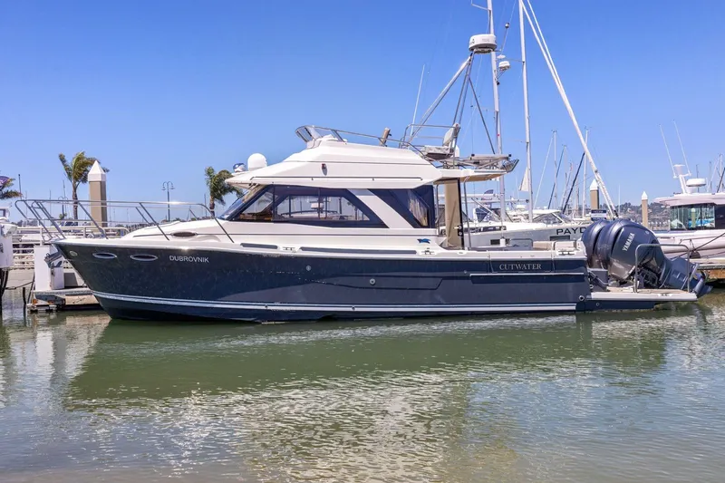 Slide: The Image of 2022 Cutwater C-32 CB yacht docked in a marina under clear blue skies. - 1