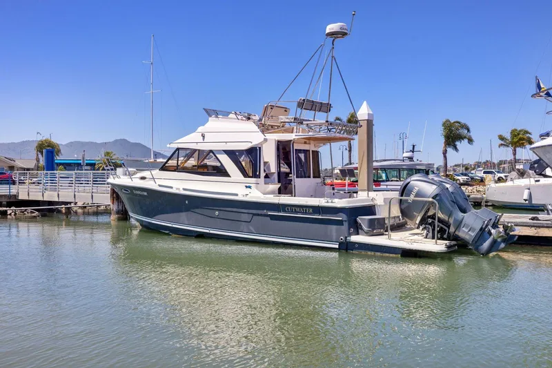 Slide: The Image of 2022 Cutwater C-32 CB boat docked in a marina under clear blue skies. - 2