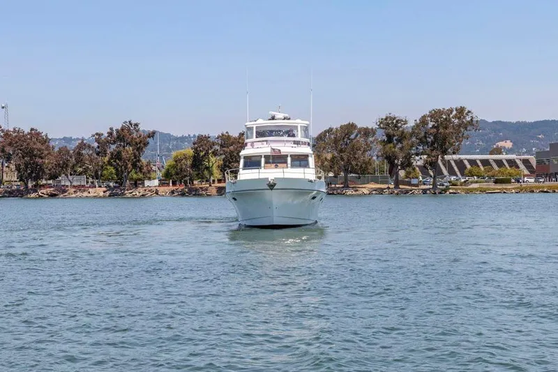 Slide: The Image of 1999 Symbol 55 yacht cruising on a calm lake with scenic shoreline backdrop. - 10