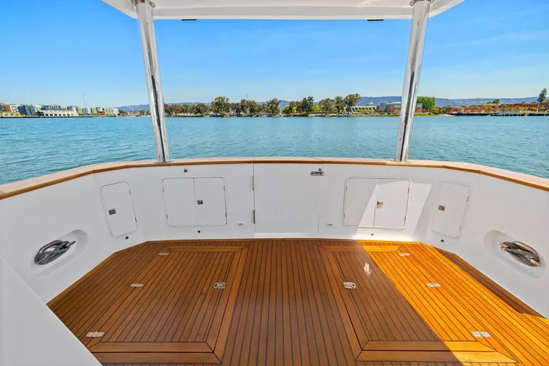 Slide: The Image of 1999 Symbol 55 yacht deck with wooden flooring, overlooking serene waterfront view. - 15