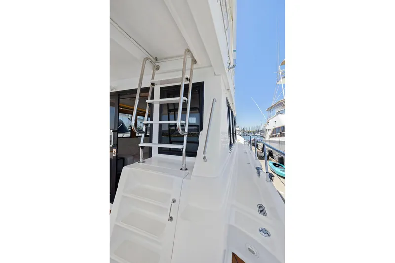 Slide: The Image of Stainless steel ladder on a 1999 Symbol 55 yacht, docked under clear blue skies. - 48