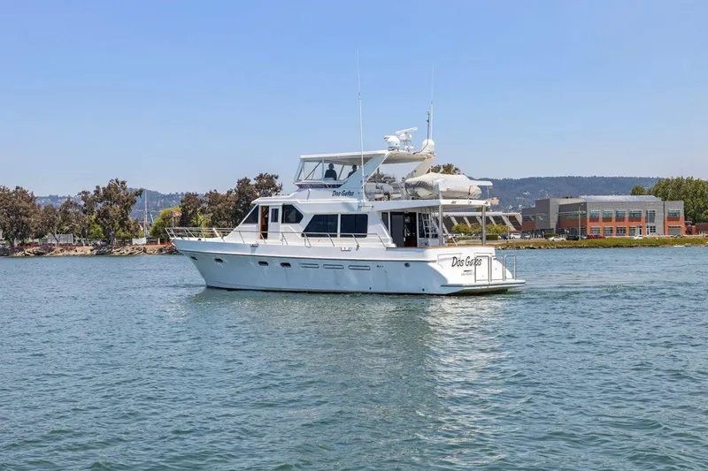 Slide: The Image of 1999 Symbol 55 yacht cruising on a calm lake near a shoreline with buildings. - 5