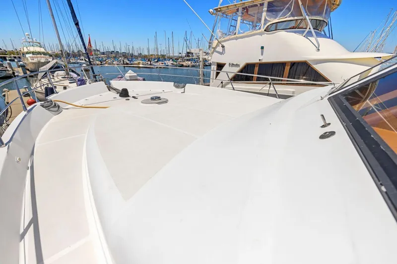 Slide: The Image of Luxury yacht deck in marina, Symbol 55 model, 1999, surrounded by boats under clear blue sky. - 52