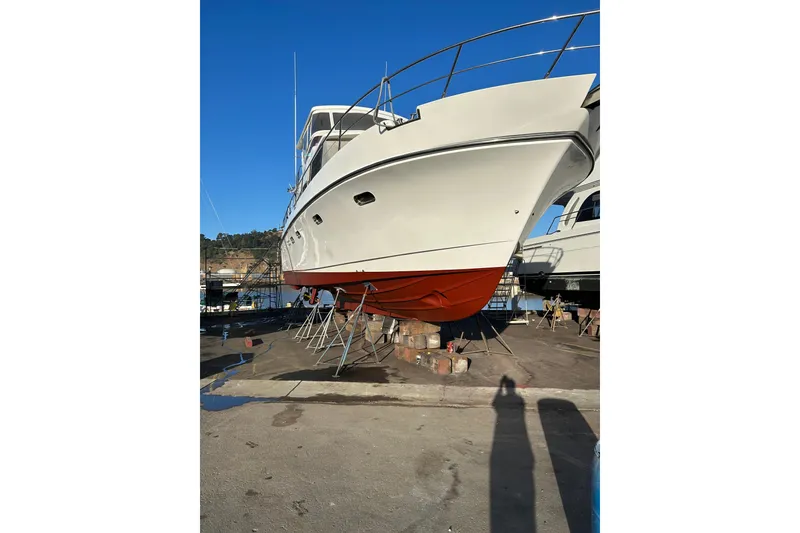 Slide: The Image of A 1999 Symbol 58 yacht on dry dock, showcasing its sleek design and red hull. - 69