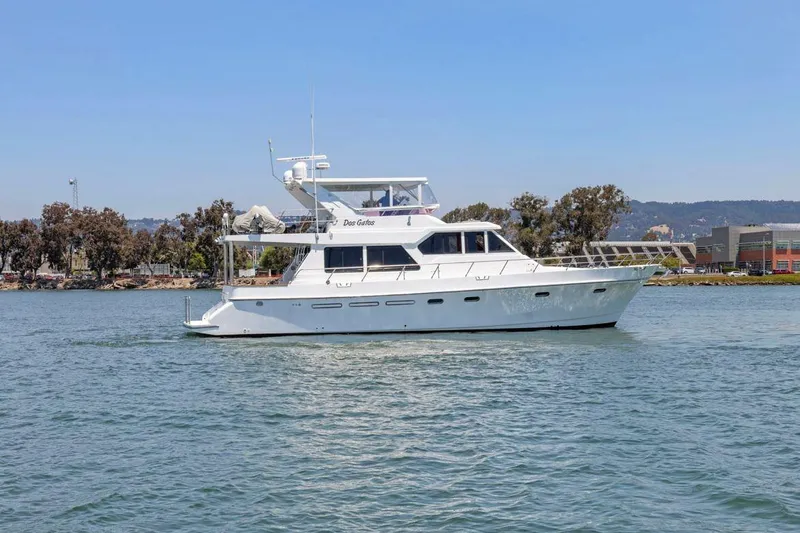 Slide: The Image of White 1999 Symbol 55 yacht cruising on a calm waterway with trees in the background. - 9