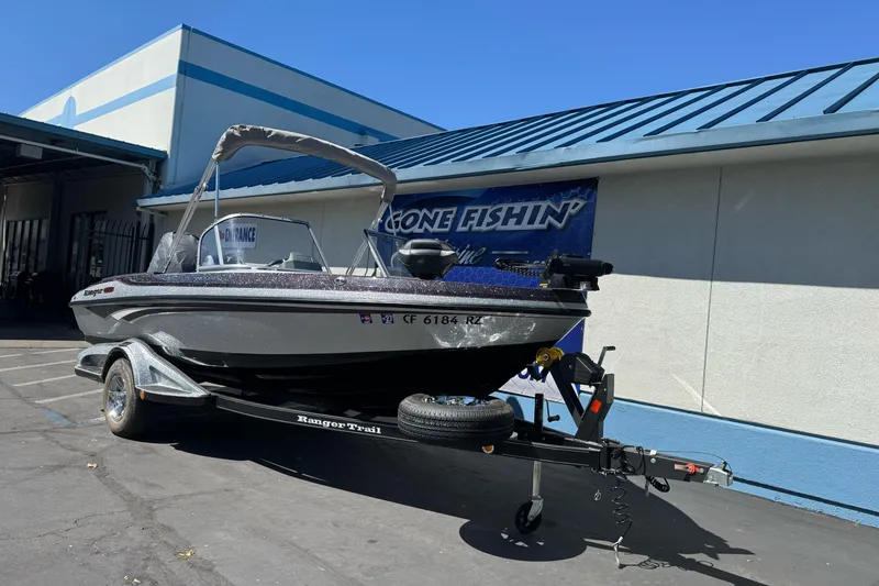 Slide: The Image of 2018 Ranger 1880MS boat on trailer outside a building under clear blue sky. - 3