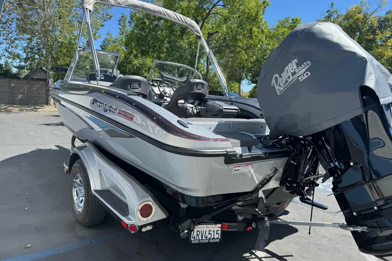 Slide: The Image of 2018 Ranger 1880MS boat on trailer, parked outdoors with trees in background. - 6