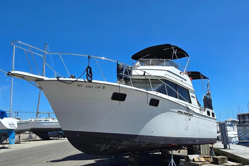 The Image of 1985 Carver 3207 Aft Cabin Motor Yacht on dry dock under clear blue sky. - 0