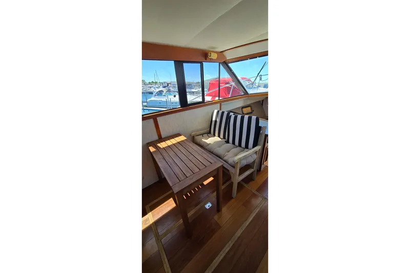 Slide: The Image of 1985 Carver 3207 Aft Cabin Motor Yacht interior with wooden table and striped cushions. - 13