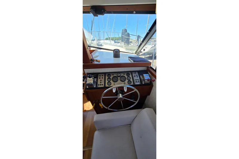 Slide: The Image of 1985 Carver 3207 Aft Cabin Motor Yacht helm with steering wheel and control panel. - 14