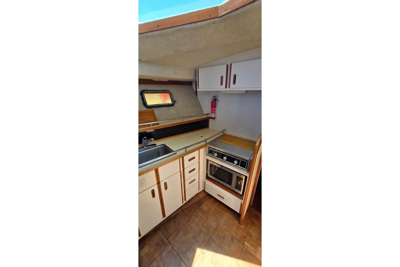 Slide: The Image of 1985 Carver 3207 Aft Cabin Motor Yacht kitchen with stove, sink, and cabinets. - 17