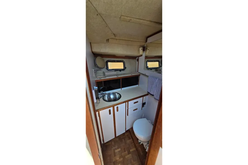 Slide: The Image of 1985 Carver 3207 Aft Cabin Motor Yacht bathroom with sink, toilet, and storage cabinets. - 19