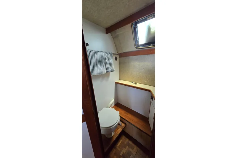 Slide: The Image of 1985 Carver 3207 Aft Cabin Motor Yacht bathroom with toilet, towel, and window. - 26