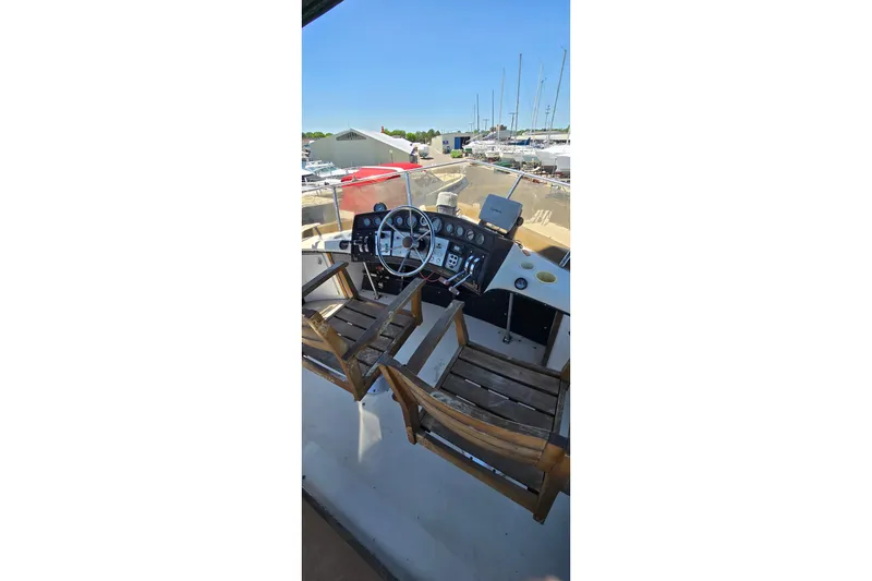 Slide: The Image of 1985 Carver 3207 Aft Cabin Motor Yacht helm with wooden chairs and control panel. - 5