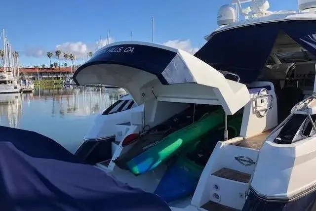 Slide: The Image of 2003 Sunseeker Predator 61 yacht docked, featuring open storage with water sports equipment. - 7