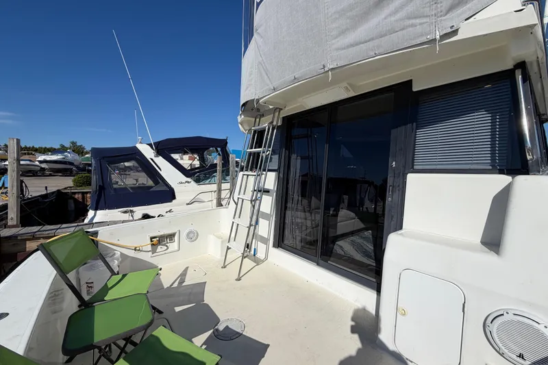 Slide: The Image of 1995 Silverton 37 Convertible yacht deck with green chairs and ladder. - 12