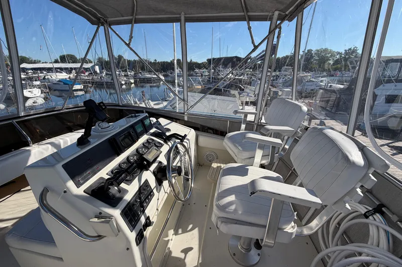 Slide: The Image of 1995 Silverton 37 Convertible yacht helm with marina view, featuring white captain chairs. - 14
