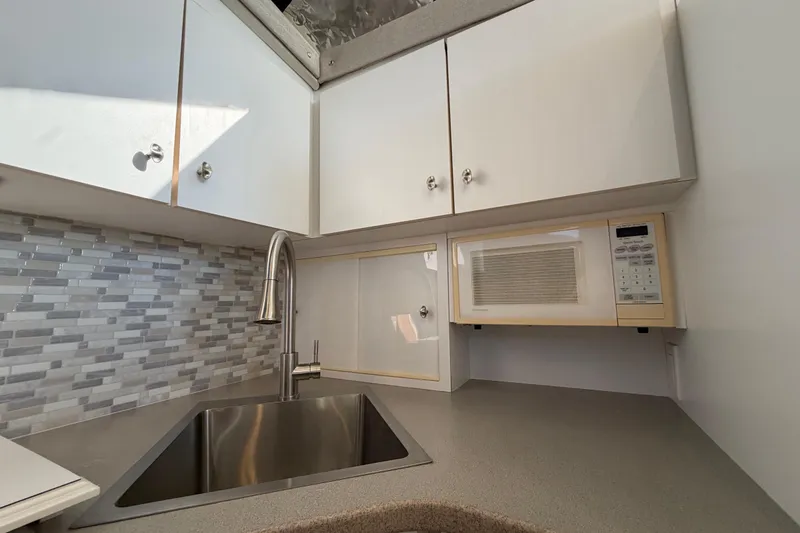 Slide: The Image of Modern kitchen area in a 1995 Silverton 37 Convertible boat with sink and microwave. - 26