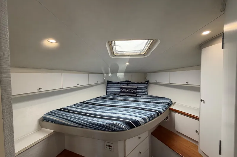 Slide: The Image of 1995 Silverton 37 Convertible cabin interior with striped bedding and overhead hatch. - 37