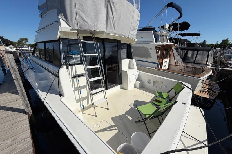 Slide: The Image of 1995 Silverton 37 Convertible yacht docked with green chairs on deck. - 9